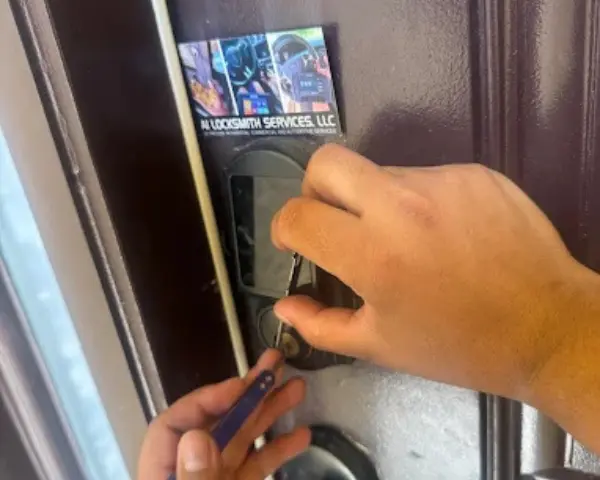 A technician uses professional lock picking tools to service a digital keypad door lock next to an A1 Locksmith Services, LLC business card, showcasing professional commercial locksmith services