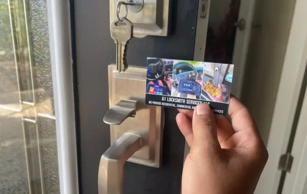 A hand holds an A1 Locksmith Services LLC business card next to a premium satin nickel door handle and a deadbolt lock with keys inserted, showcasing a premier locally owned locksmith company