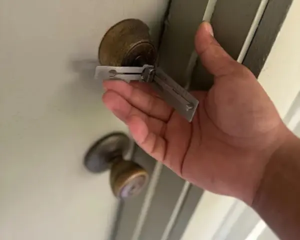 A technician uses a professional Lishi lock picking and decoding tool to open a brass residential door knob lock cylinder, demonstrating trusted residential locksmith services